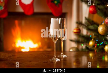 Due bicchieri riempiti di champagne sul tavolo accanto all'albero di Natale Foto Stock