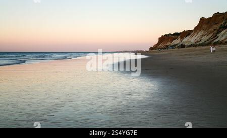 Viaggiare a Algarve Portogallo - i turisti a piedi sulla spiaggia Praia Falesia vicino alla città di Albufeira durante la serata ebb Foto Stock