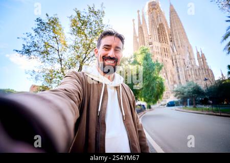 Giovani simpatici uomini caucasici che fanno un selfie davanti alla Sagrada Familia di Barcellona. Foto Stock