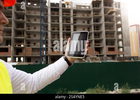 Ingegnere edile che controlla la costruzione di edifici con un tablet digitale Foto Stock