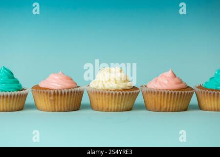 Colorati cupcake appena sfornati di fila su sfondo blu Foto Stock