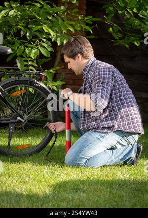 Giovane seduto sull'erba, parcheggia e tira fuori le gomme Foto Stock