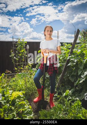 Giovane donna con stivali di gomma che lavora nel giardino del cortile Foto Stock