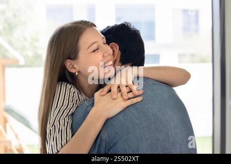 Felice eccitata giovane moglie che abbraccia marito a occhi chiusi Foto Stock