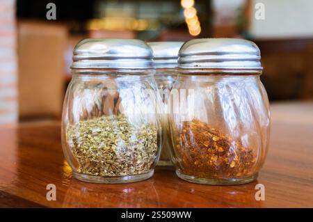 Bicchiere di sale di formaggio e peperoni shakers sul tavolo di legno nel ristorante. Foto Stock