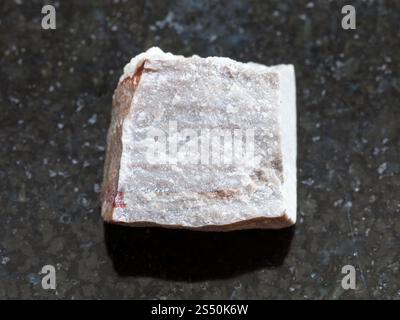 Le riprese in modalità macro di minerale naturale campione di roccia - riolite ruvida sulla pietra di granito scuro dello sfondo Foto Stock