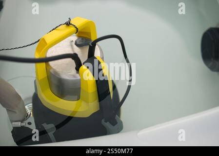Pompa sommergibile in acciaio inox con manico giallo brillante e supporti per tubi in acqua idromassaggio. Concentrati sulla pompa. Filo collegato e cavo di alimentazione visibile Foto Stock