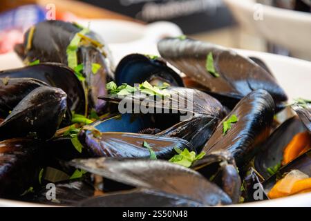 Cozze al vapore servite in una ciotola guarnita con prezzemolo fresco Foto Stock