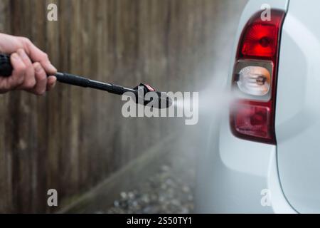 Foto ravvicinata di un uomo che lava la sua auto con una grande testa d'acqua di un karcher all'aria aperta. Pulizia e disinfezione. Le misure di sicurezza durano Foto Stock