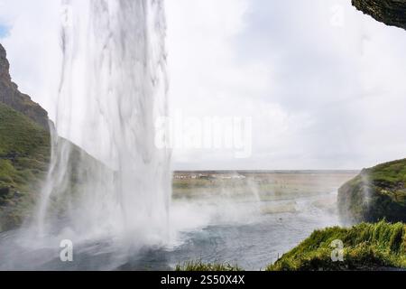 Viaggio in Islanda - vista della cascata di Seljalandsfoss dalla grotta del Katla Geopark sulla costa meridionale dell'Atlantico islandese a settembre Foto Stock