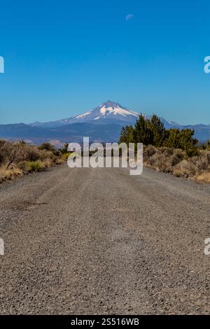 Remote Gravel Road che conduce alla montagna innevata sotto Clear Blue Sky, Cove Palisades State Park, Oregon Foto Stock