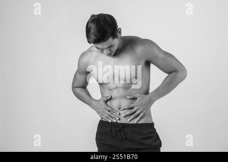 Il giovane uomo muscolare ha dolore addominale isolato su sfondo bianco. Il giovane e bellissimo uomo muscolare ha dolore addominale isolato su bianco Foto Stock
