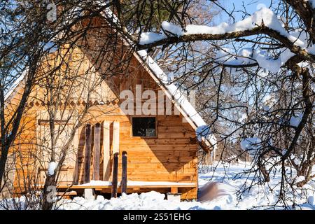 vista di un piccolo cottage in legno e ampi sci. Vista di un piccolo cottage in legno e ampi sci nella soleggiata giornata invernale nella regione russa di Smolensk Foto Stock
