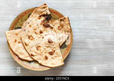 Cucina indiana - Tandoori Roti di tutto il grano pane piatto sulla piastra in ottone sulla tabella grigia Foto Stock