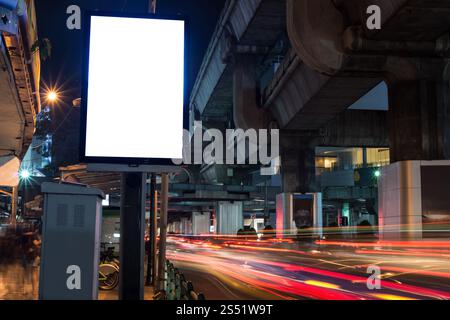 Cartellone bianco con spazio per copiare i messaggi di testo o i contenuti promozionali, cartellone informativo pubblico accanto alla strada di notte. Cartellone vuoto Foto Stock