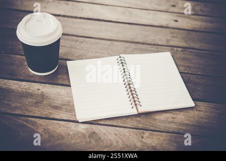 Blank notebook e la tazza di caffè su di un tavolo di legno. Foto Stock