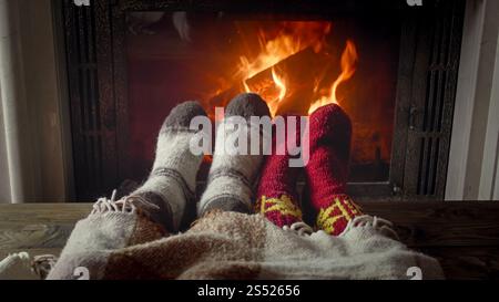 Immagine ravvicinata tonificata di una coppia in calze di lana che giacciono sotto una calda coperta sul caminetto. Foto ravvicinata tonificata della coppia in calze di lana che giacciono sotto caldo Foto Stock