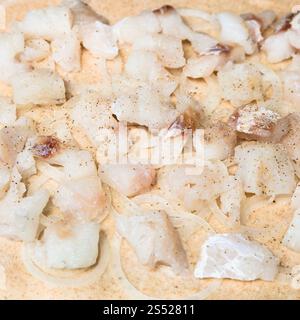 La cottura della torta - ripieno di pesce crudo pezzi e agli anelli di cipolla in pasta Foto Stock