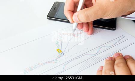 Foto ravvicinata di un uomo d'affari che analizza i tassi di vendita delle azioni utilizzando un grafico finanziario. Immagine ravvicinata di un uomo d'affari che analizza i tassi di vendita delle azioni utilizzando Foto Stock