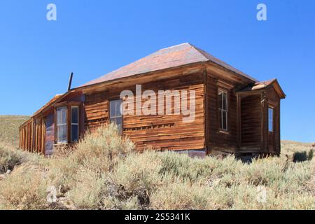Una piccola, vecchia casa con un tetto inclinato si trova su una collina. La casa è circondata da erba alta e lui è abbandonato Foto Stock