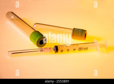 Provette per analisi del sangue vuote e siringa isolate su sfondo arancione. Provette e siringa per analisi del sangue vuote Foto Stock
