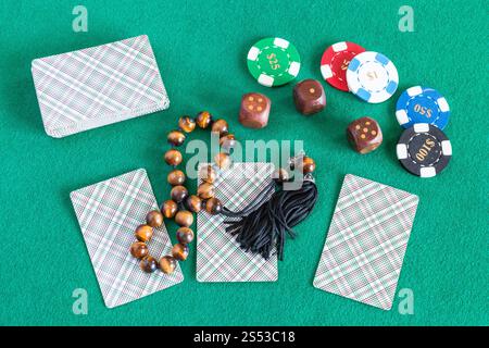 Vista dall'alto di mazzi di carte, dadi di legno, casinò di token e preoccupazioni sfere sul tavolo verde Foto Stock