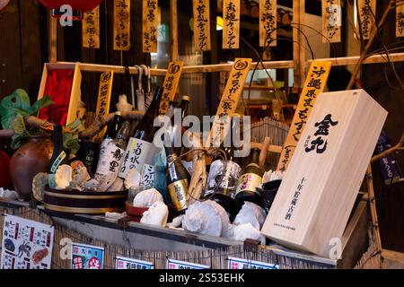 Bottiglie di sake e decorazioni di pesce all'esterno di un ristorante a Kokusai dori, Naha, Okinawa Foto Stock