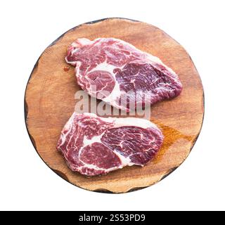 due bistecche di manzo di marmo grezzo su un tagliere di legno isolato su sfondo bianco Foto Stock