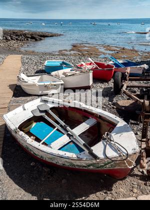 Immagine di vecchie barche a remi dipinte in legno che giacciono sulla spiaggia di mare accanto al molo. Foto di vecchie barche a remi in legno dipinte che si trovano sulla spiaggia Foto Stock