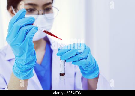 Scienziato in possesso di una provetta per il campione di sangue infetto da Coronavirus covid-19. Analisi del DNA del sangue in laboratorio con provette per il prelievo di campioni di sangue e. Foto Stock