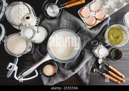 Prova del lievito nel latte riscaldato in una pentola piccola: Direttamente sopra il lievito protetto nel latte circondato da altri ingredienti del pane e utensili da cucina Foto Stock