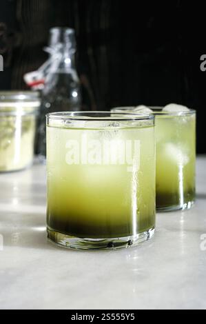 Due bicchieri di Matca Soda con cubetti di ghiaccio: Acqua frizzante mescolata con sciroppo semplice di matcha servita in bicchieri di roccia Foto Stock
