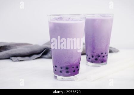 Due bicchieri di Purple Sweet Potato Bubble Tea: Boba con cubetti di ghiaccio e cannucce in silicone trasparente su sfondo bianco Foto Stock