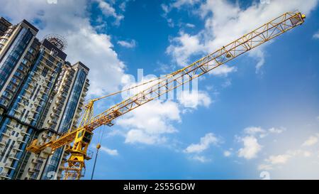 Foto di un'alta gru in cantiere contro il cielo blu e i grattacieli. Immagine di una gru alta in cantiere contro il blu Foto Stock