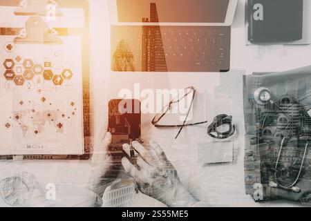 Vista superiore della smart medico lavora con il telefono cellulare e il computer portatile e di uno stetoscopio in legno scuro, scrivania con la costruzione di esposizione Foto Stock