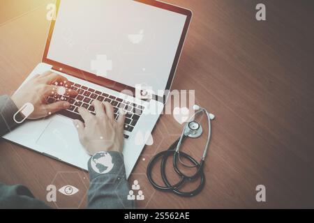 Vista superiore della smart medico lavora con lo stetoscopio e laptop e tablet digitale computer in legno scuro, scrivania con schema Vr Foto Stock