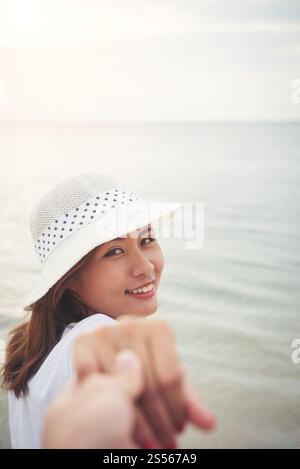 Ragazza prendere il suo fidanzati per la spiaggia. Donna che mantiene la sua man mano per godere della spiaggia. Rilassante vacanza giovane nell'amore. Foto Stock
