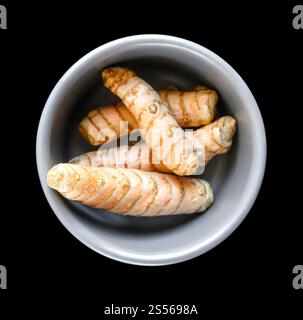 Radice di curcuma in una ciotola isolata su sfondo nero. Vista dall'alto. Radice di curcuma in una ciotola isolata sul nero Foto Stock