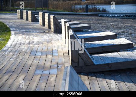 Lettini in legno ricoperti di gelo su una passeggiata sulla spiaggia durante una fredda mattinata invernale. L'ambiente vuoto suggerisce tranquillità e solitudine, con il te Foto Stock