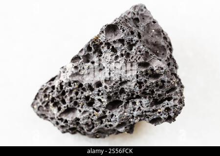 primo piano di un campione di minerale naturale proveniente dalla raccolta geologica - Roccia nera di Pumice non lucidata su sfondo di marmo bianco Foto Stock