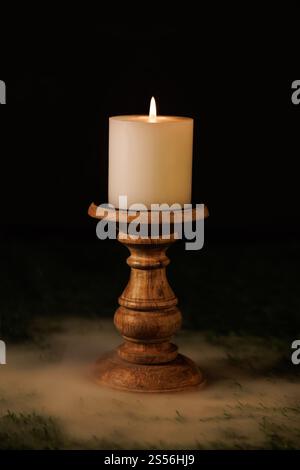 Una candela bianca su un candelabro di legno con un'atmosfera nebbiosa intorno a loro. Foto Stock