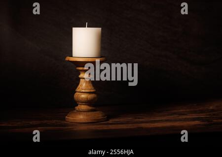 Candela bianca singola su un candelabro di legno. La candela non è accesa. Foto Stock