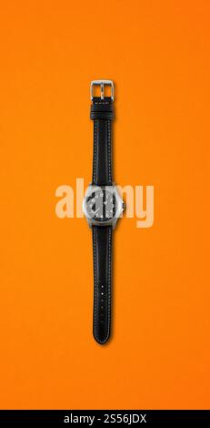 Orologio da polso nero isolato su sfondo arancione. Orologio da polso isolato su sfondo arancione Foto Stock