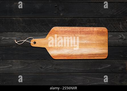 Tagliere in legno su fondo in legno nero. Tagliere in legno isolato su fondo in legno nero Foto Stock