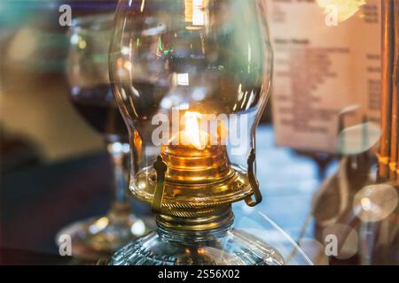 lampada vintage a cherosene sul tavolo del ristorante con un bicchiere o un vino rosso atmosfera romantica Foto Stock