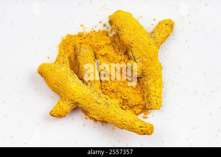 Vista dall'alto del cumulo di polvere e radici curcuma primo piano sulla piastra in ceramica grigia Foto Stock