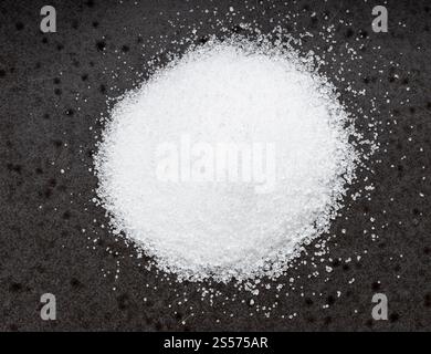 vista dall'alto del cumulo di sostituto dello zucchero - estratto cristallino di pianta di stevia primo piano su piastra di ceramica nera Foto Stock