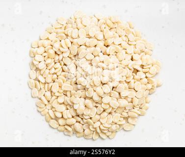 pila di urad dal grezzo (grammo nero diviso) i fagioli si avvicinano alla piastra in ceramica grigia Foto Stock