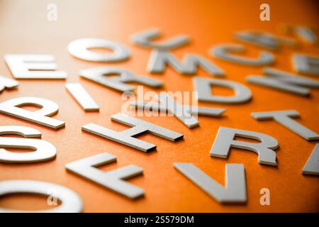 Vista ravvicinata di una pila di lettere piene miste. Concetto educativo su sfondo arancione. Vista ravvicinata pile di lettere miste. Sfondo arancione Foto Stock