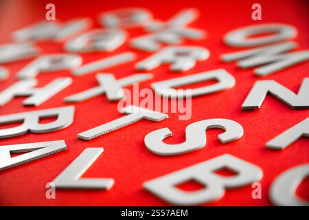 Vista ravvicinata di una pila di lettere piene miste. Concetto educativo su sfondo rosso. Foto ravvicinata con lettere miste. Sfondo rosso Foto Stock